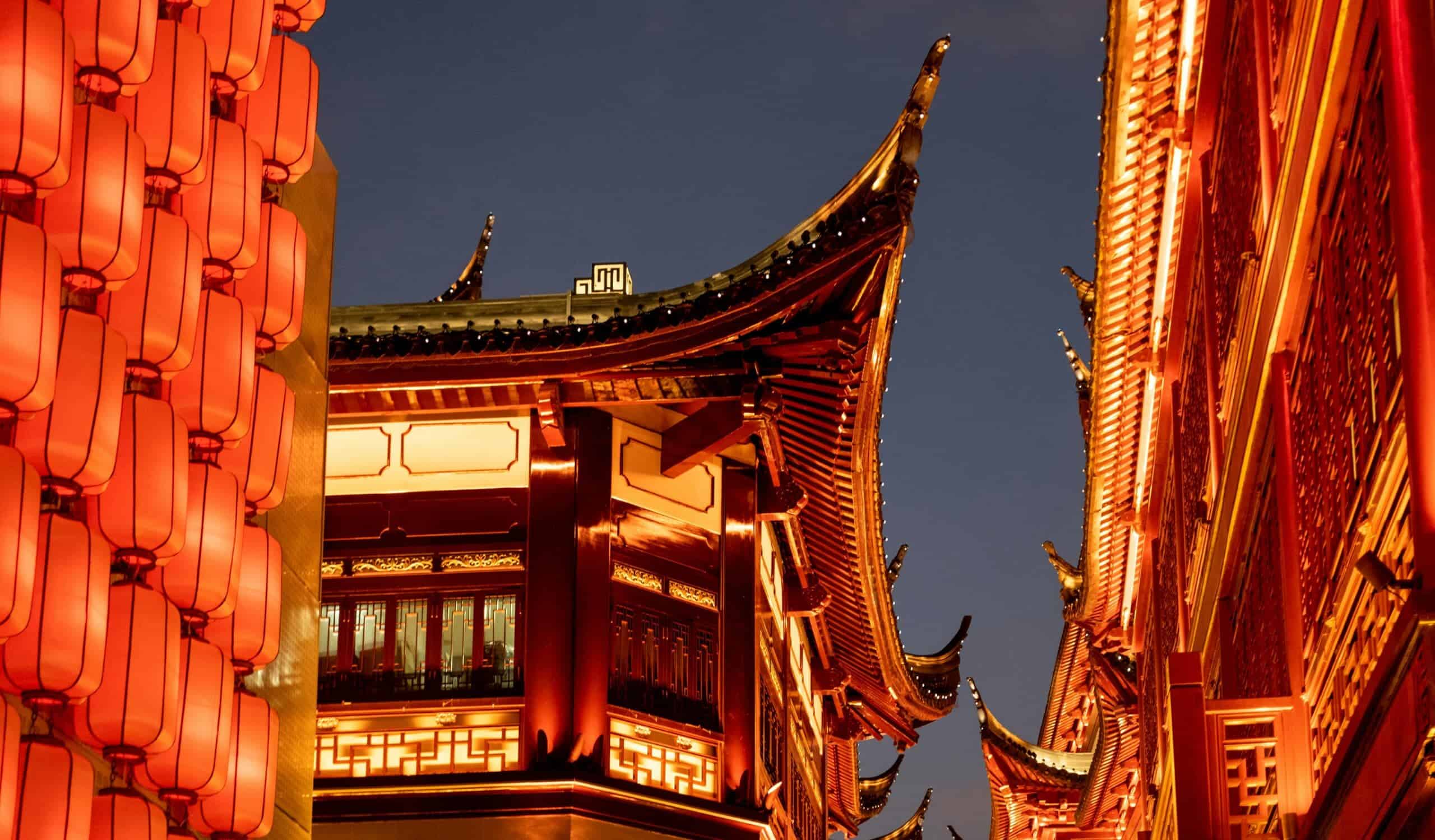 Bright traditional Chinese lanterns and ornate temple rooftops illuminated at night, showcasing vibrant red and gold colours, intricate architectural details, and cultural symbolism for authentic Chinese heritage.