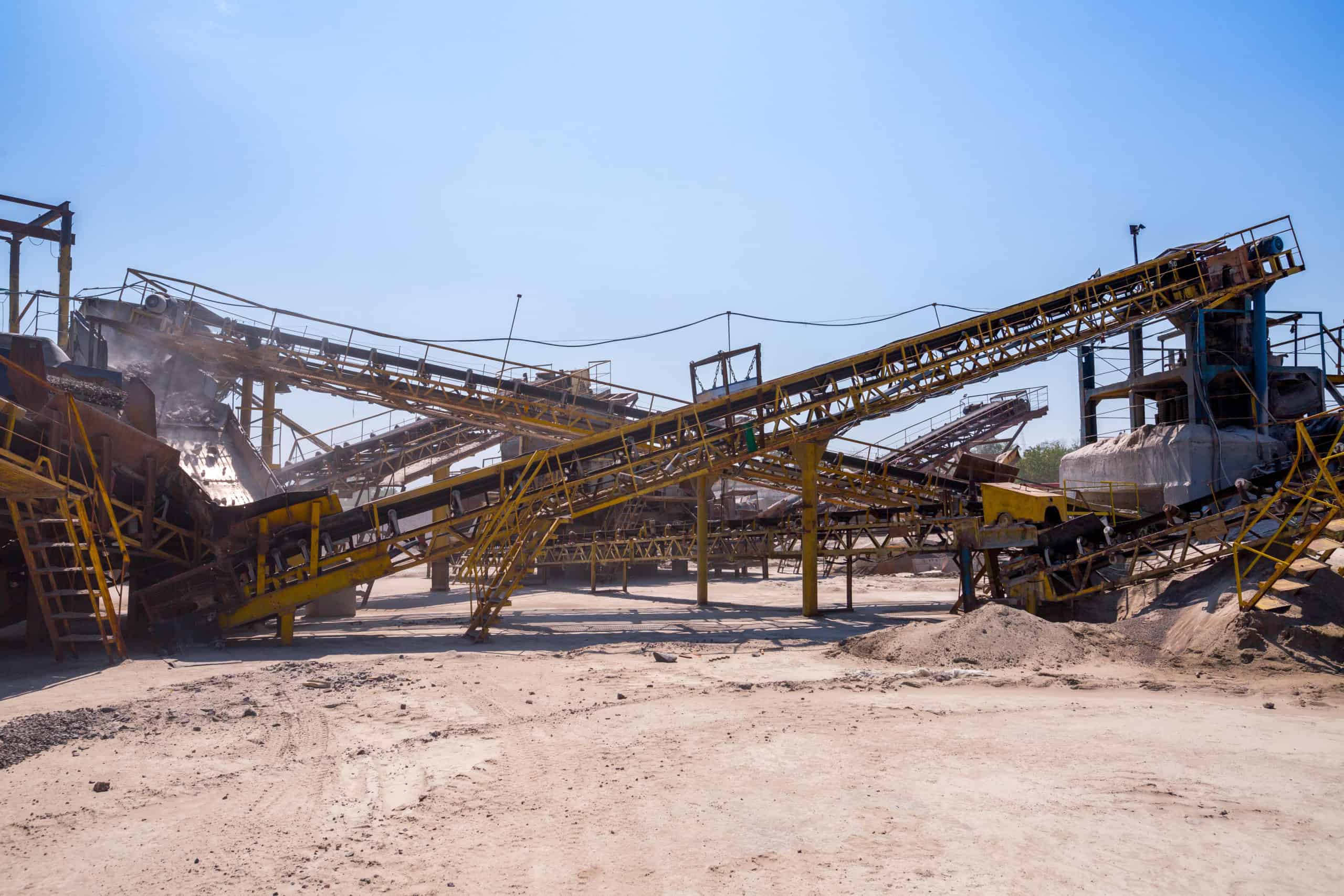 Active aggregate mining and crushing facility with conveyor systems and processing equipment at a quarry operation — industrial extraction site subject to air quality permitting, dust emissions compliance, and environmental regulatory consulting by EDGE Engineering.