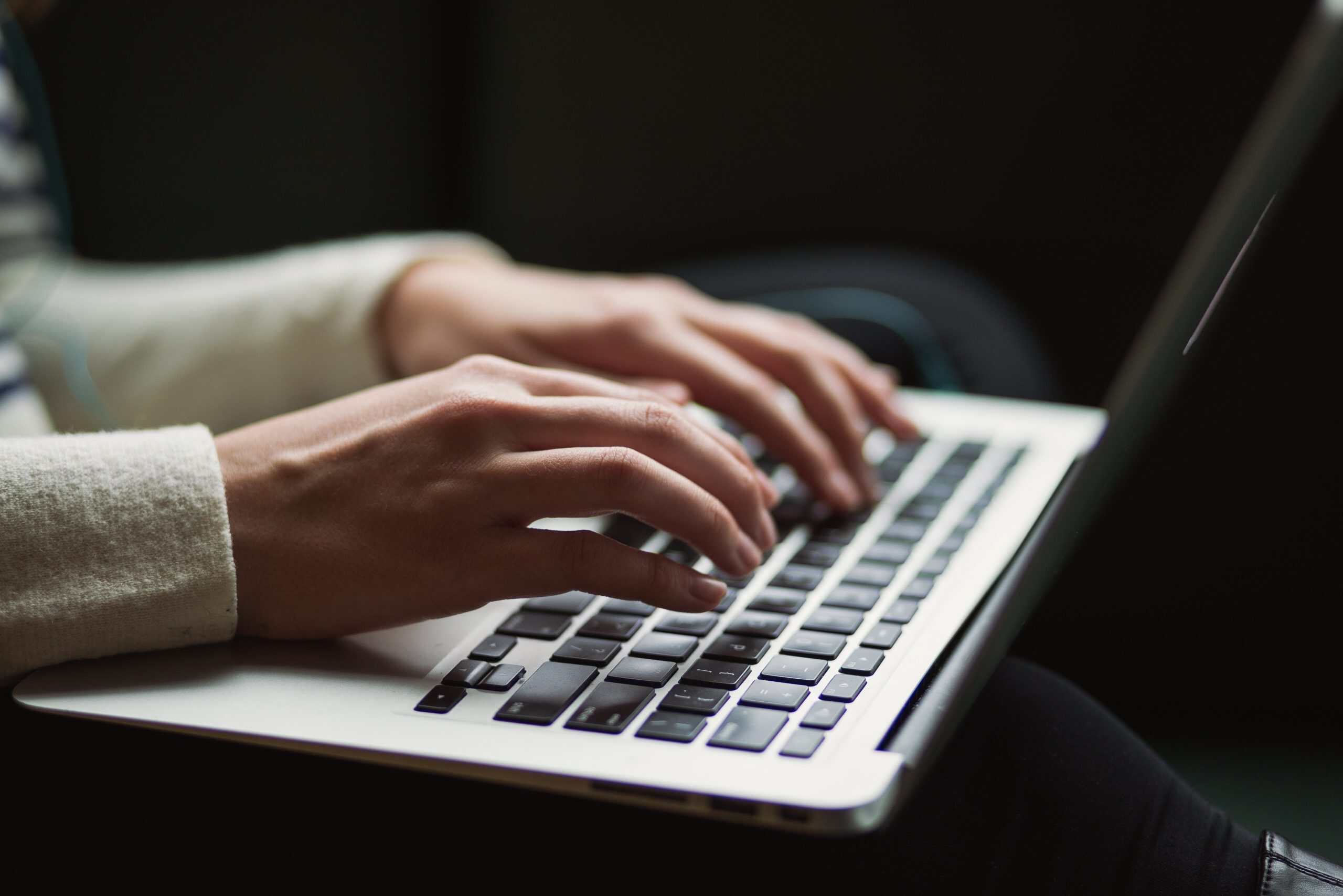 Woman using her laptop to create her profile using online dating tips for profile writing.