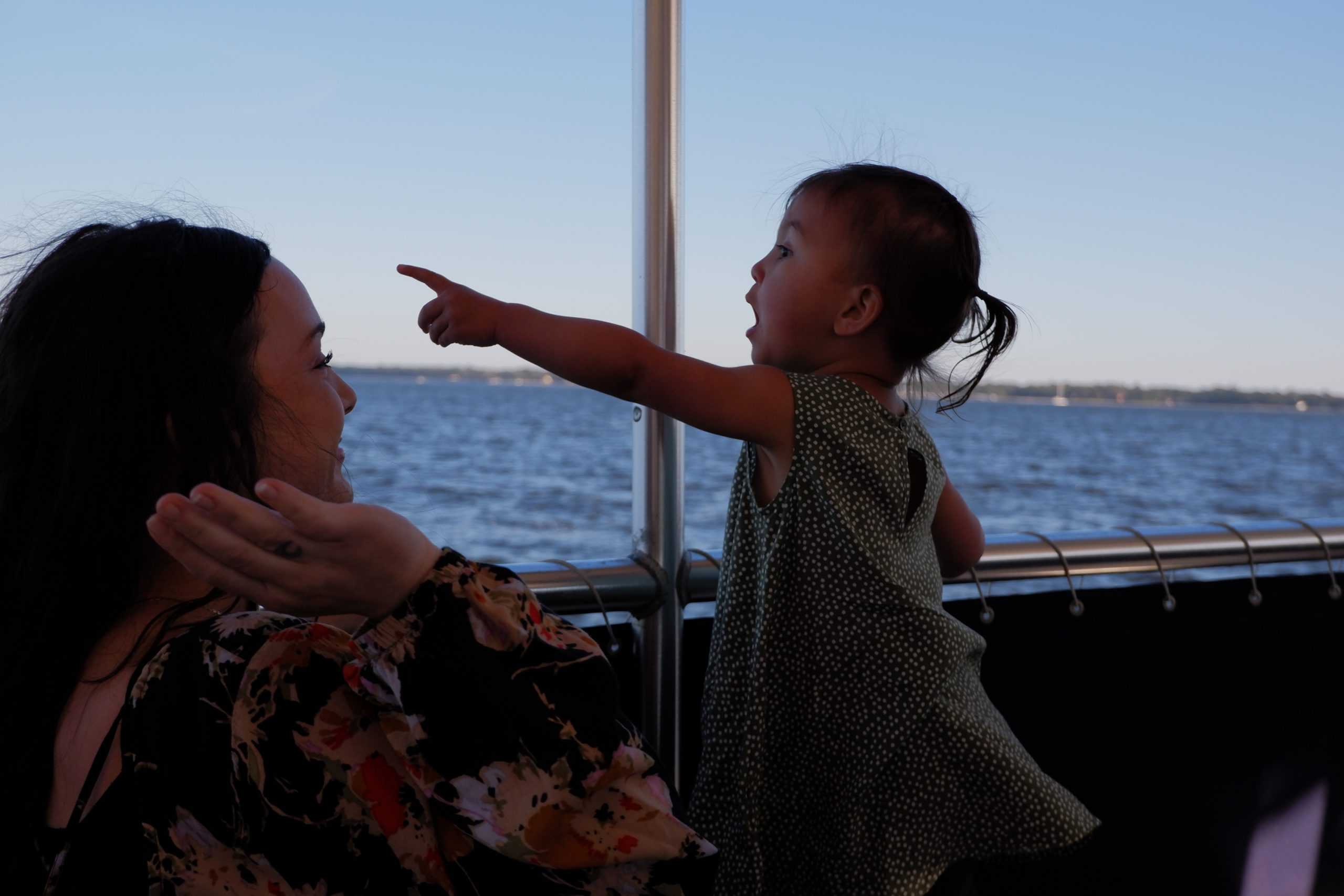 Young kid excitedly pointing to something in the distance from the boat. Family boat charters Charleston, SC