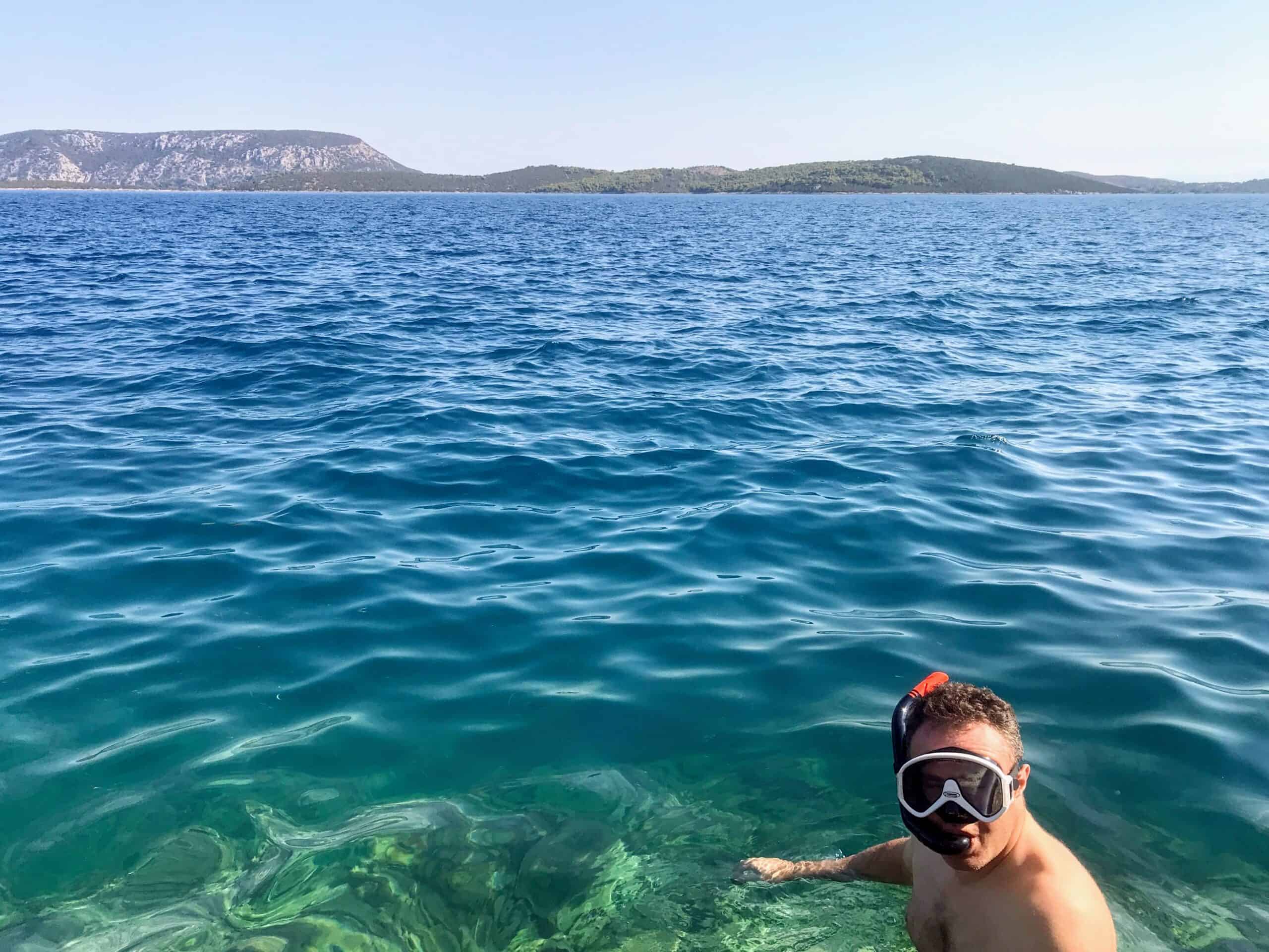 Snorkelling in Ermioni Greece. Andy snorkelling in the crystal clear sea on Mandrakia side of Ermioni in Greece. He's wearing a black and white snorkel mask and snorkel.