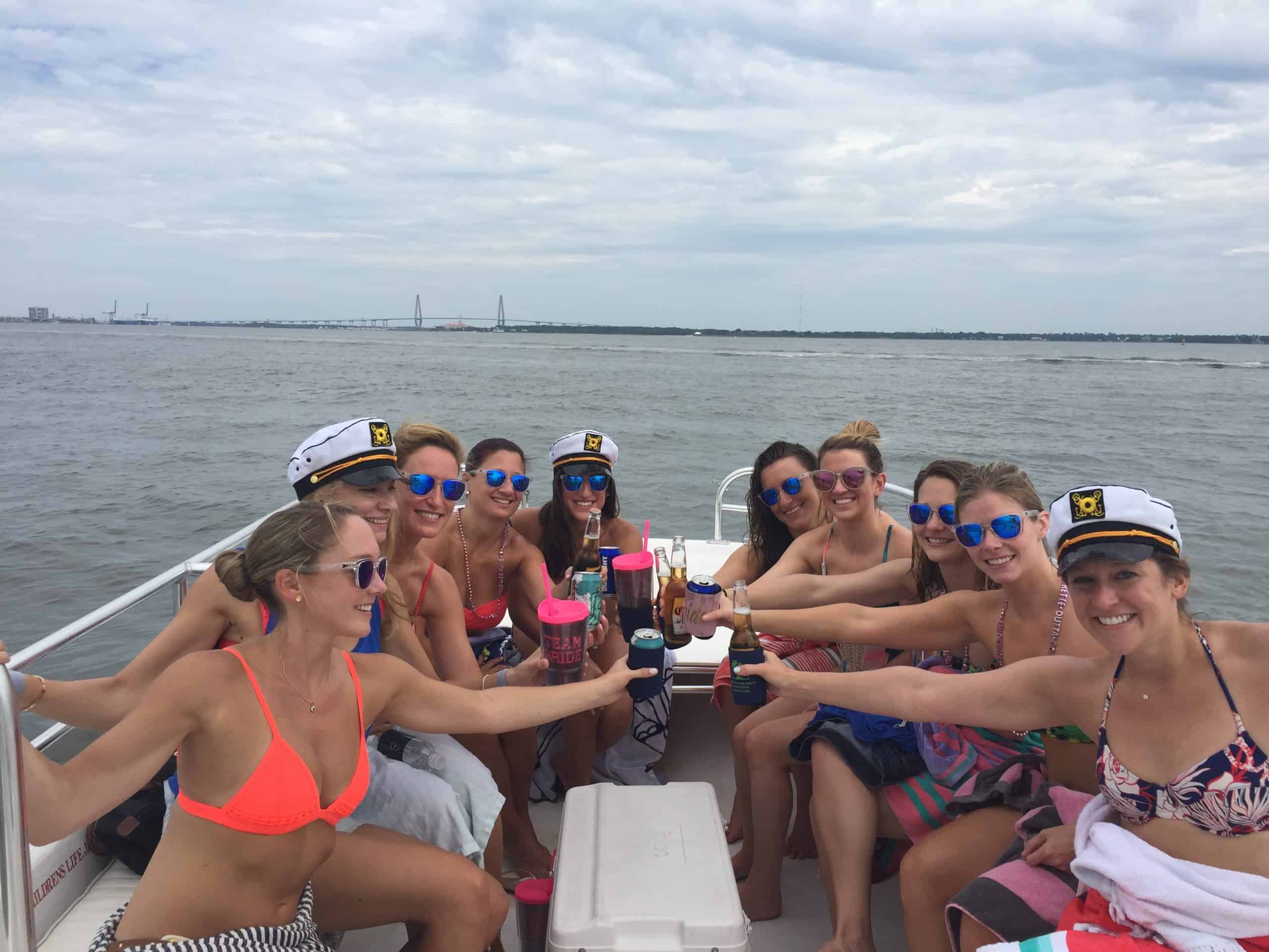 Group of women using their drinks to cheers together on the boat. Private booze cruise