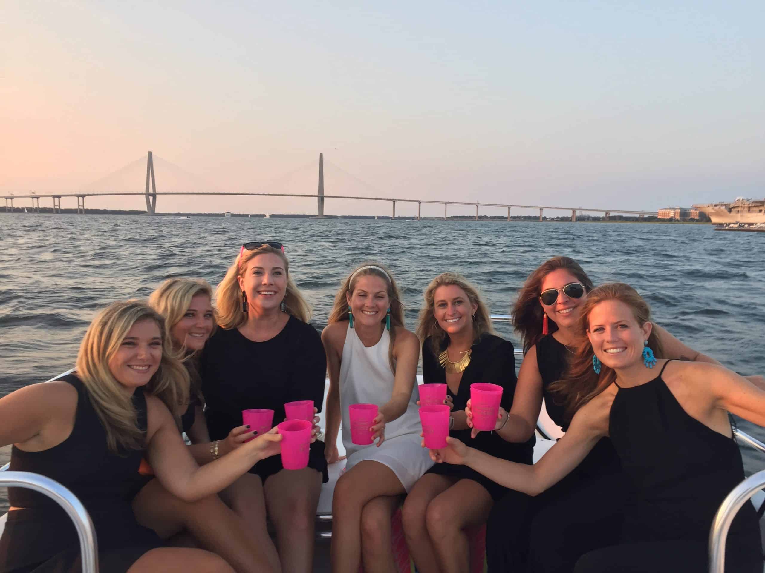 Group of women dressed up on the boat, toasting with their drinks. Private booze cruise