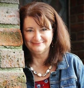 smiling lady standing next to a brick wall.