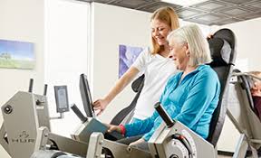 Physical therapist assisting senior on exercise machine