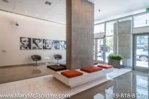Sleek modern lobby at 321 10th Ave featuring polished concrete floors, a large concrete pillar with integrated bench seating, and an art gallery wall showcasing iconic black-and-white portraits.