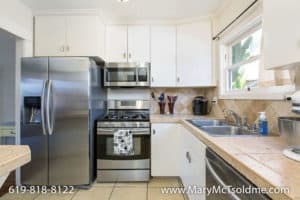 Bright kitchen at 3164 Thorn St in North Park with white cabinetry, stainless steel appliances, and a tan tile backsplash and countertop.