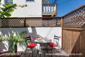 Outdoor seating area at 3164 Thorn St in North Park with a mosaic-top bistro table, red-cushioned chairs, and a privacy lattice fence.
