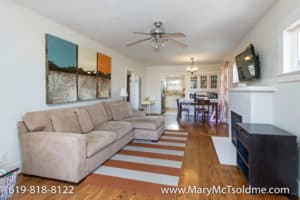 Open-concept living room at 3164 Thorn St in North Park with a tan sectional, striped area rug, and an unobstructed view into the dining area and kitchen.
