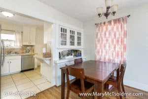 Dining area at 3164 Thorn St in North Park with a dark wood table, built-in white hutch, and a glimpse into the tiled kitchen.