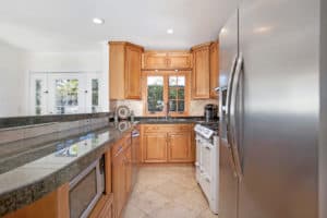 Kitchen at 3704 Maple St in North Park featuring wood cabinetry, granite countertops, a white vintage-style range, and a stainless steel refrigerator.