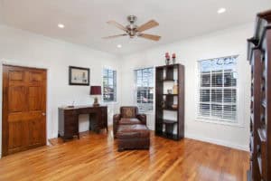 Home office at 3704 Maple St in North Park featuring hardwood floors, a vintage wooden desk, a leather armchair with an ottoman, and a ceiling fan.