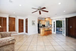 Spacious pool house living area at 3704 Maple St in North Park with tiled flooring, a ceiling fan, a small kitchenette, and French doors leading to the pool.