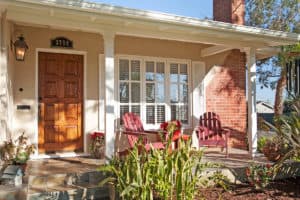 Craftsman-style front porch at 3704 Maple St in North Park with a rich wood front door, red Adirondack chairs, and a classic red brick chimney.