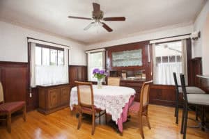 Traditional dining room at 2873 Upas St in North Park featuring dark wood wainscoting, a built-in china cabinet, hardwood floors, and a table set with a lace tablecloth.