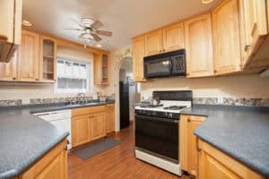 Well-appointed kitchen at 2873 Upas St in North Park featuring light wood cabinets, dark granite-style countertops, a white gas range with a black microwave above, and warm wood flooring.