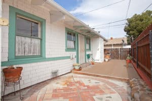 Classic white shingle Craftsman home at 2873 Upas St in North Park featuring teal window trim and a patterned brick patio.