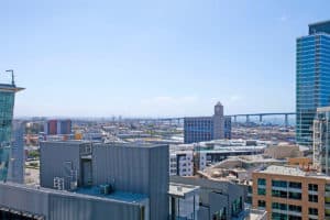 Skyline view from 321 10th Ave overlooking downtown San Diego, showing the Coronado Bridge, San Diego Bay, and surrounding urban architecture under a clear blue sky.