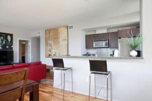 Open-concept living space at 321 10th Ave featuring a granite breakfast bar with modern stools, hardwood floors, a red leather sofa, and large-scale abstract wall art.