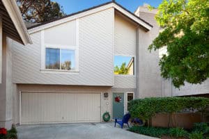 Townhouse exterior at 5474 Caminito Borde in Mission Valley featuring neutral siding, a two-car garage, and a gated patio entryway.