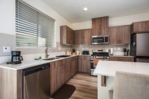 Upgraded kitchen at 5235 Beachfront Cove Unit 102 featuring a NEW tile backsplash, under-cabinet lighting, and maintained modern finishes.