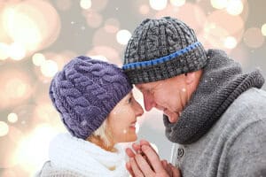 Couple staring happily into each other's eyes while snow falls around them.