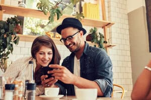Guy and gal friends looking at a post over coffee.