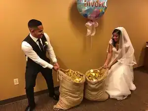 Jeune couple en costume de mariage avec sacs de pièces d'or et ballon "Divorce".