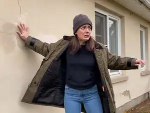 Femme inquiète appuyée contre un mur extérieur en hiver.