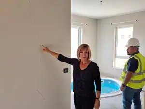 Inspection d'une fissure dans un mur intérieur par une femme et un homme en sécurité.