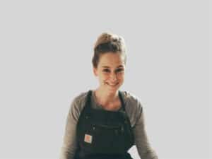 Frau mit Latzhose lächelt in die Kamera