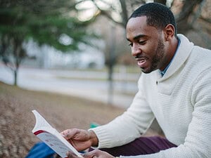 Shy man sitting outside and reading about dating advice for shy guys.