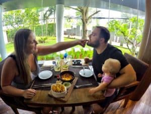 A romantic couple enjoying a meal at a table with a baby.