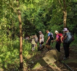 Hikers exploring a Cambodia jungle trail near Angkor Wat, walking through tropical forest, hidden temple ruins, and remote backcountry landscapes.