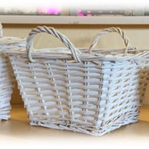 A white wicker basket with handles on a wooden table.