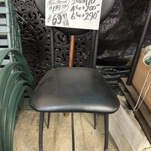 Black cushioned chair with metal legs in a storage area.