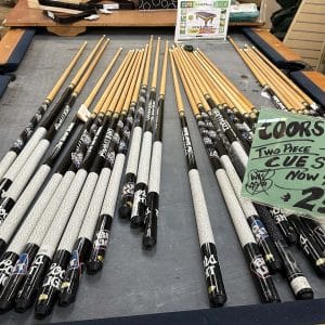 Multiple sets of pool cues neatly arranged on a table for sale.