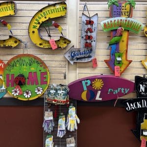 Colorful welcome signs and decor for home and parties displayed on a wall.