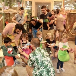 Children and adults engaging in an interactive dinosaur exhibit at a museum.