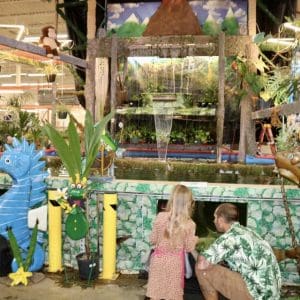 Two children explore a colorful aquarium exhibit with sea-themed decorations.