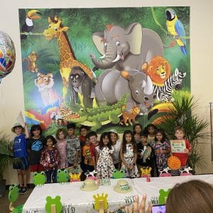 Children posing in front of a colorful jungle animal mural at a party.