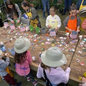 Children decorating cookies at a large table outdoors.