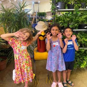 Four kids enjoying a playful moment with a large sunflower indoors.
