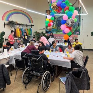 People gathered at a colorful celebration with balloons and decorations.