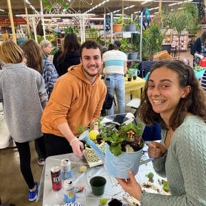 Two people enjoying drinks and smiling at an outdoor market.