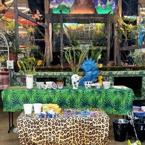 A vibrant market stall with colorful plants and patterned tablecloths.