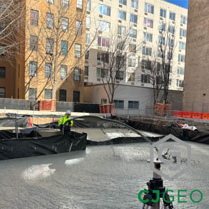 A construction worker placing lightweight cellular concrete into a large excavated area for load reduction.
