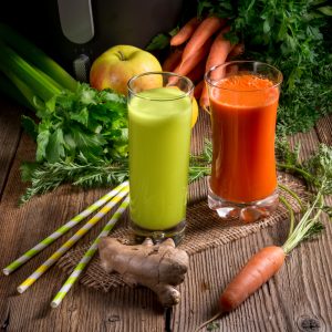 freshly squeezed vegetable juices with two glasses and assorted vegetables