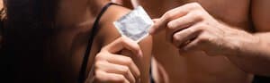 A verdade Sobre Os Preservativos Texto alternativo: Pessoa segurando uma embalagem de preservativo, representando sexo seguro, prevenção do HIV e outras ISTs.