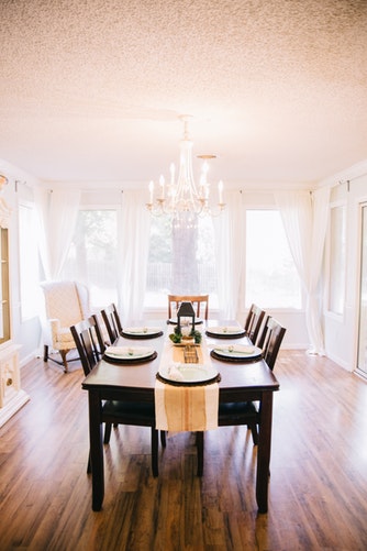 A dining room with wooden table and chairs. Table is set with plates